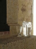 Jug of water and glass goblet in front of fireplace within ancient sandstone walls