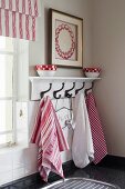 Dish towels hanging on white, lacquer coat rack next to a window in a kitchen corner