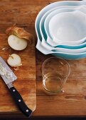 Set of baking dishes on wooden table next to sliced onion on chopping board