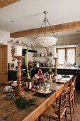 Festively set table in rustic, English country-house kitchen