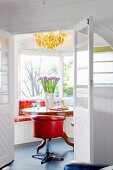 View into bright room with orange, retro swivel chair at round wooden table