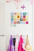 White children's wardrobe with attached princess costumes; above it a colorful alphabet and decorative butterflies
