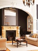 Mirror on ornately carved mantelpiece behind classic lounge area with two sofas