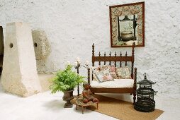 Herrschaftlicher antiker Stuhl neben Vogelkäfig und Pflanzengefäss auf Loggia eines spanischen Wohnhauses