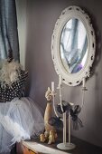 Candelabra and ornaments on chest of drawers below wall-mounted mirror