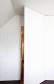 Attic room with white panelled wall and open door