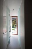 Schmaler Gang und Blick durch offene Glastür auf Gartentür in zeitgenössischer Wohnung