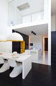 Minimalistischer, offener Wohnraum in Weiß und Schwarz mit gelben Akzenten