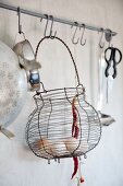 Eggs in old wire basket and other kitchen utensils hanging from butchers' hooks