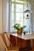Country-style dining area - paraffin lamp hanging above wooden dining table at window