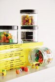 Screw-top jars of colourful boiled sweets on stack of comics