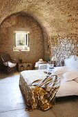 Rustic bedroom with stone walls and vaulted ceiling