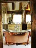 View through open door of vintage-style, free-standing copper bathtub in rustic setting