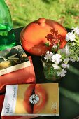 Bücher, Blume und Topf auf einem Gartentisch