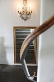 Stone staircase reflected in gilt-framed mirror with blurred handrail in foreground
