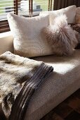 Helles Sofa mit Kissen und Decke in kuschliger Felloptik