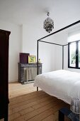 Bed with modern canopy in modernised period bedroom with pale wooden floor