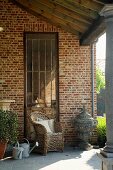 Wicker chair in front of old rusty metal door on veranda with column