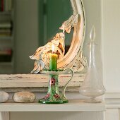 Kerzenständer aus Porzellan vor Spiegel mit floral verziertem Holzrahmen