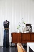 Schneiderpuppe in Abendkleidung neben 50er Jahre Sideboard mit Vasen und schwarzweissem Frauenportrait