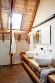 Waschschüsseln auf offenem Holzunterschrank in modernem Bad im Dachgeschoss