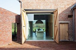 Open, barn-style doors - view from courtyard of brick housing complex into modern dining room