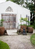 Buddha and animal statues around planters in front of simple house with weathered wooden door