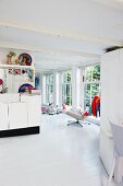 Offener Wohnraum in Weiß mit einzelnen, bunten Dekorationsstücken