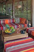 Cheery outdoor furniture upholstered in bright stripes and bowls with tropical fruit on a natural wooden table