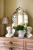 Bouquet of roses, busts and mirror on chest of drawers