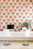 Designer swivel chairs at white console table against wall with floral wallpaper