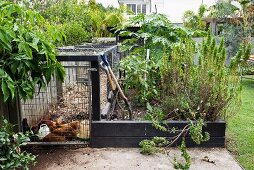 Hühnergehege und eingefasste Beete im Nutzgartenteil eines Wohnhauses