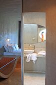 Concrete as predominant material in minimalist hotel room with ensuite bathroom; interesting arrangement of mirror images