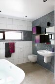 Modern bathroom with washstand and small colourful cabinets mounted on wall with grey mosaic tiles