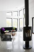 Free-standing log burner next to modern Spaghetti chair in open-plan interior with lounge area in eclectic mix of styles
