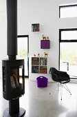Free-standing log burner and classic, black shell chair in modern living room
