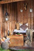 Cosily furnished shelter in woods with cushions on wire bench and simple lunch on wooden trunk