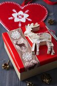 Gift box festively decorated with wooden reindeer pendant and reindeer-patterned ribbon