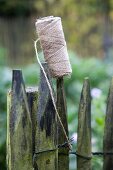 Roll of garden twine stuck on point of paling fence