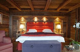 Modernes Doppelbett mit gepolstertem Kopfteil an Wand in rustikaler Holzhütte