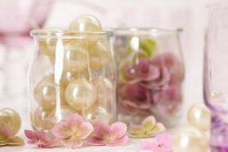 Perlen und rosa Hortensienblüten in Gläsern