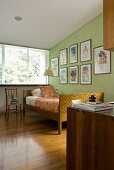 Bedroom with skilfully crafted bed in front of framed posters on wall painted lime green