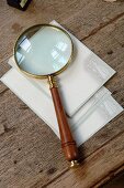 Magnifying glass and postcards with old-fashioned motif of couple on old table top