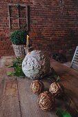 Balls of wood and stone carved with floral patterns on rustic table in front of brick facade