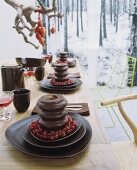 Gestaltete Dessert-Gedecke auf Esstisch - Baumkuchen mit Johannisbeerrrispen auf Schalenset aus dunkelbrauner Keramik