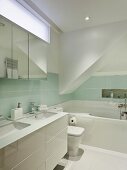 Designer bathroom with white washstand against wall with pastel wall tiles
