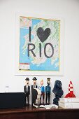 Map with lettering reading 'I love Rio' on wall above collection of comic character figurines