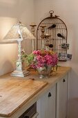 Shabby chic decor with bouquet of hydrangeas and stylised birdcage on rustic kitchen counter