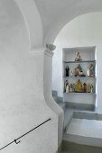 Religious figurines in niche in white stairwell with grey treads