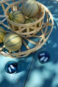Melons in two wooden mesh baskets of different sizes on blue wooden table